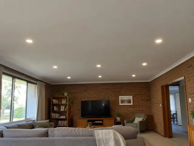 Living room with recessed ceiling downlights, brick walls, sofa and TV in Shortland